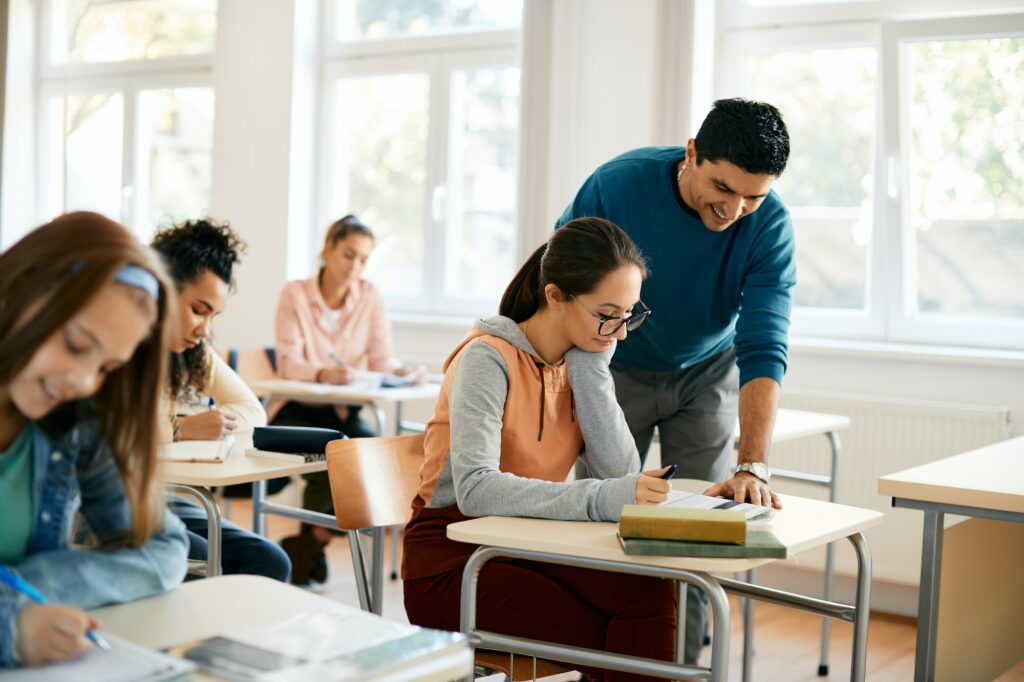 Female high school student leaning with teacher's help in the classroom.